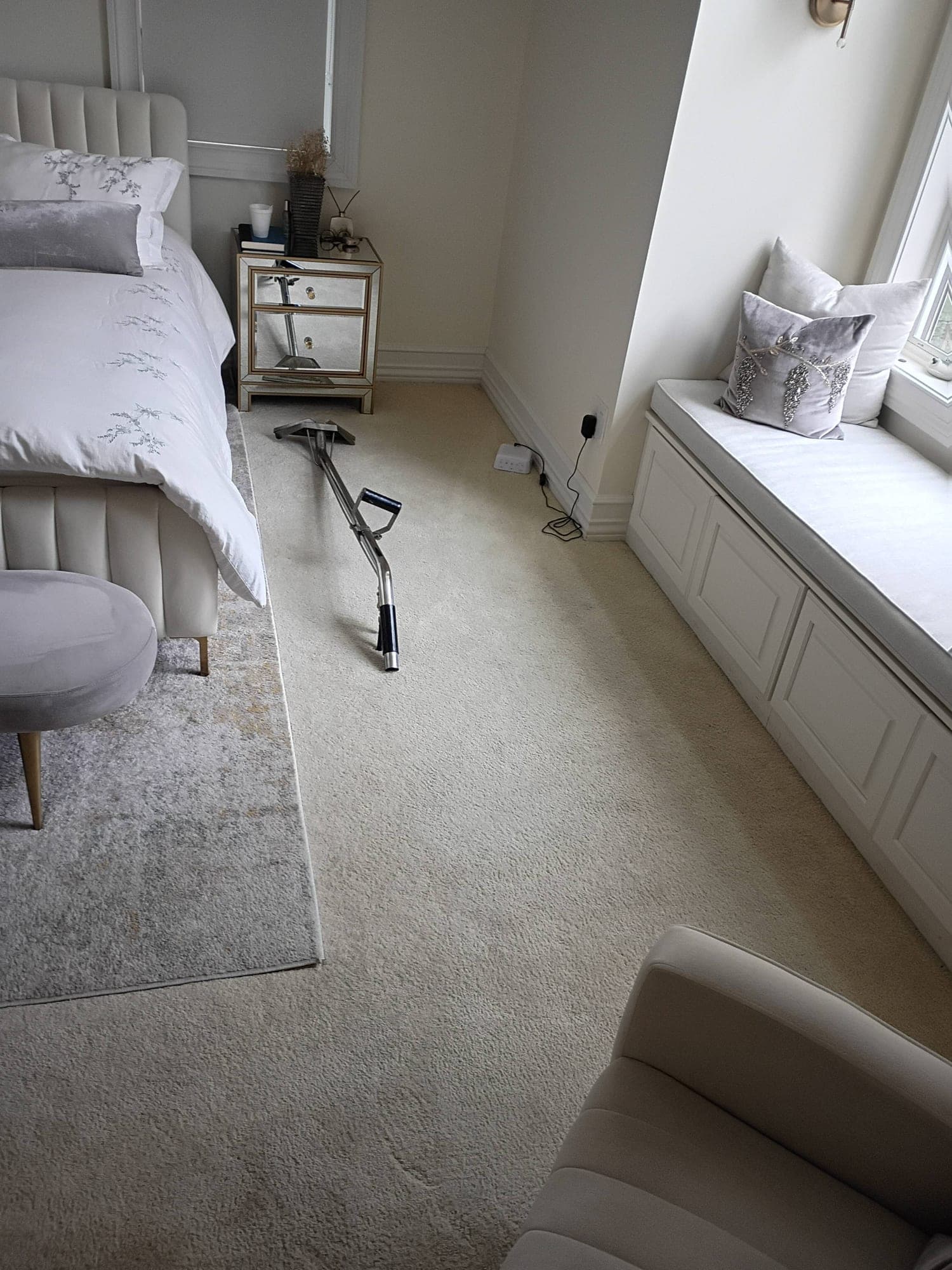 Wide bedroom view with window seat and carpet cleaning wand on the carpet