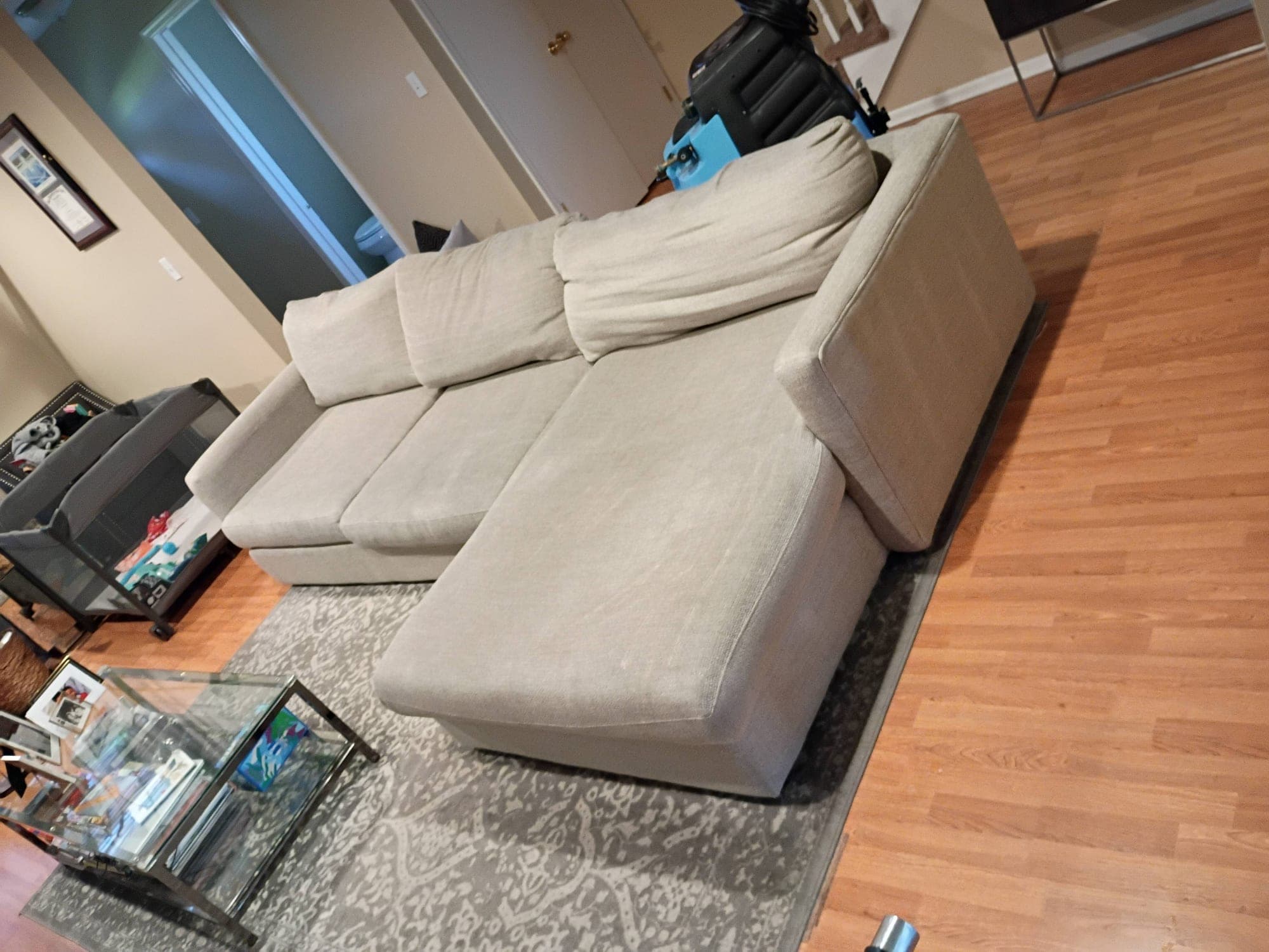 Beige sectional sofa after cleaning from an elevated angle with equipment visible
