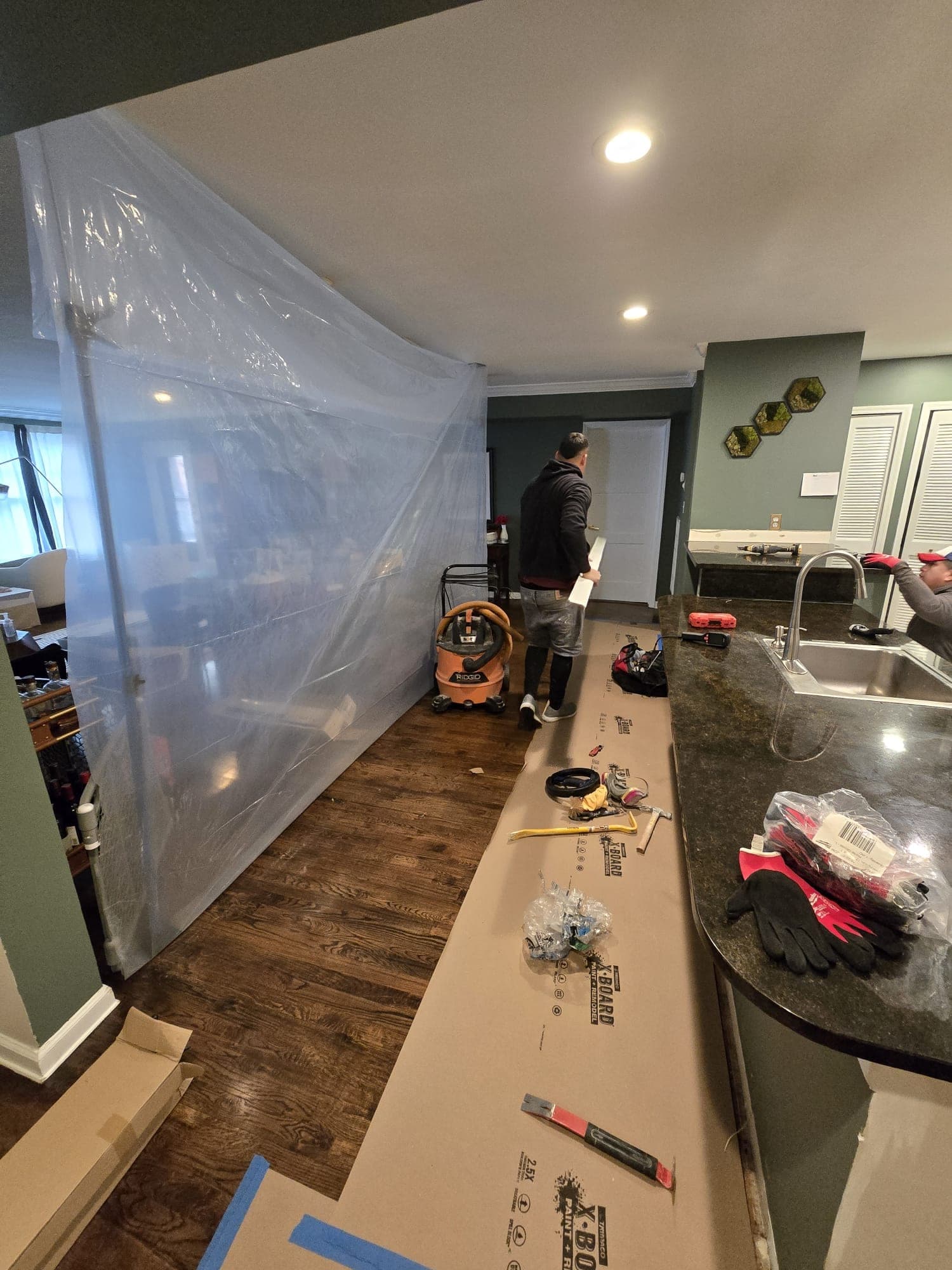 Poly sheeting containment wall isolating a living room while floor protection goes down