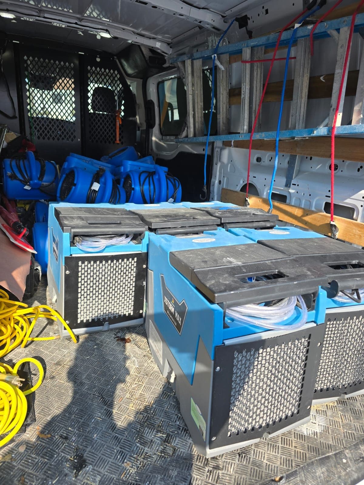 Cargo van loaded with air movers, dehumidifiers and ladders ready for a water damage job