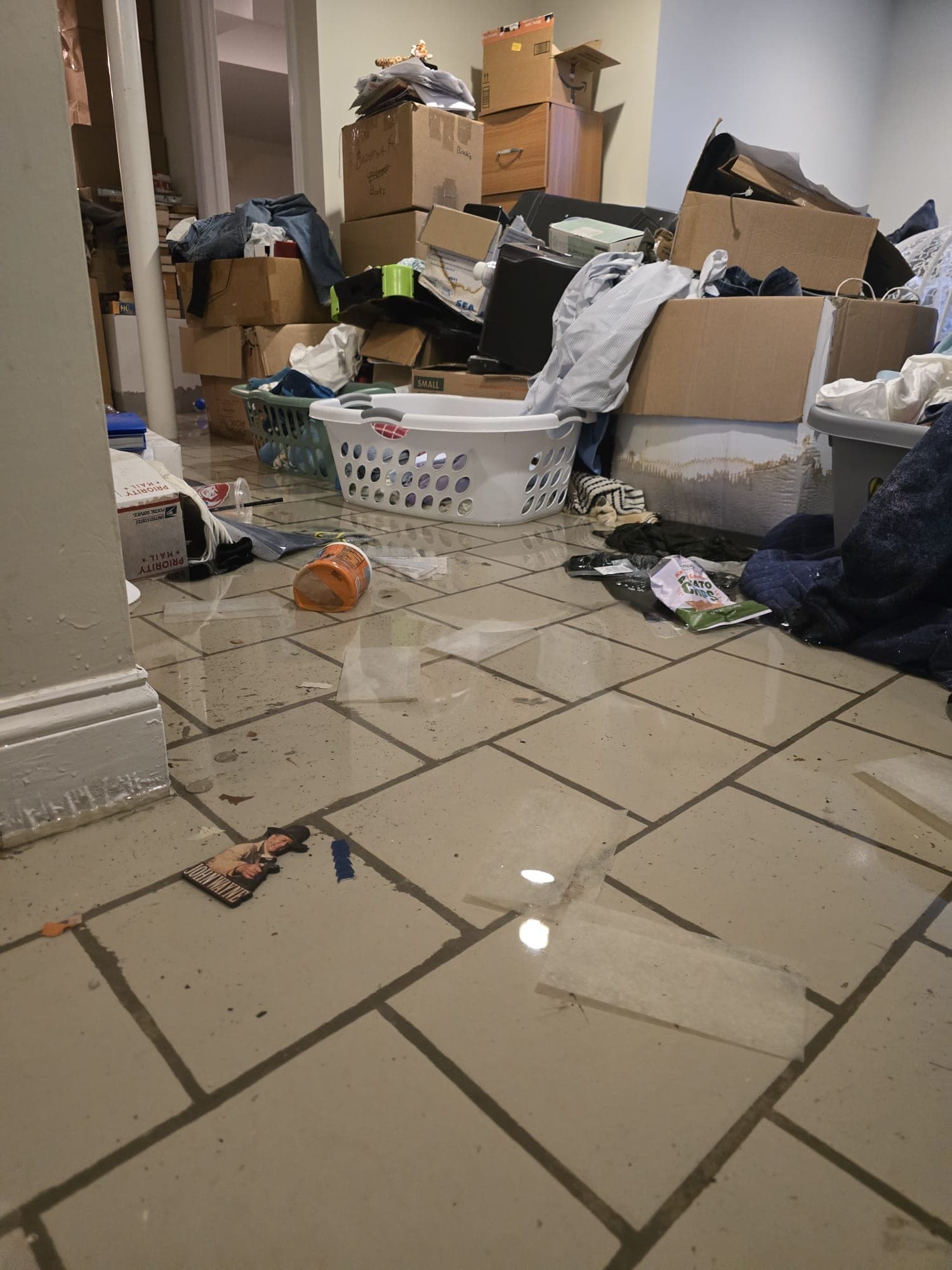 Standing floodwater across a basement floor with cardboard boxes wicking water
