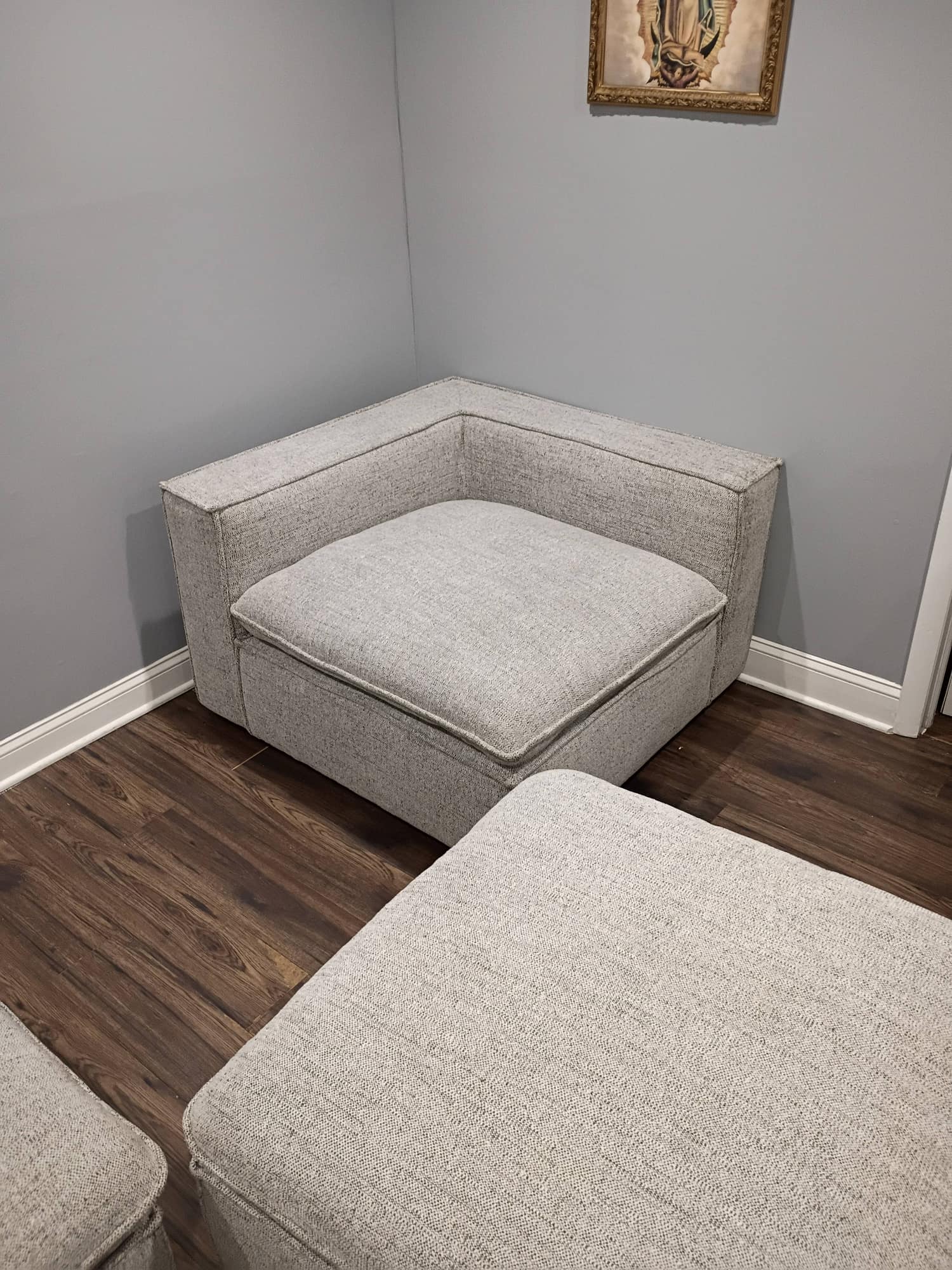 Gray modular corner sofa piece on dark wood floor during upholstery cleaning
