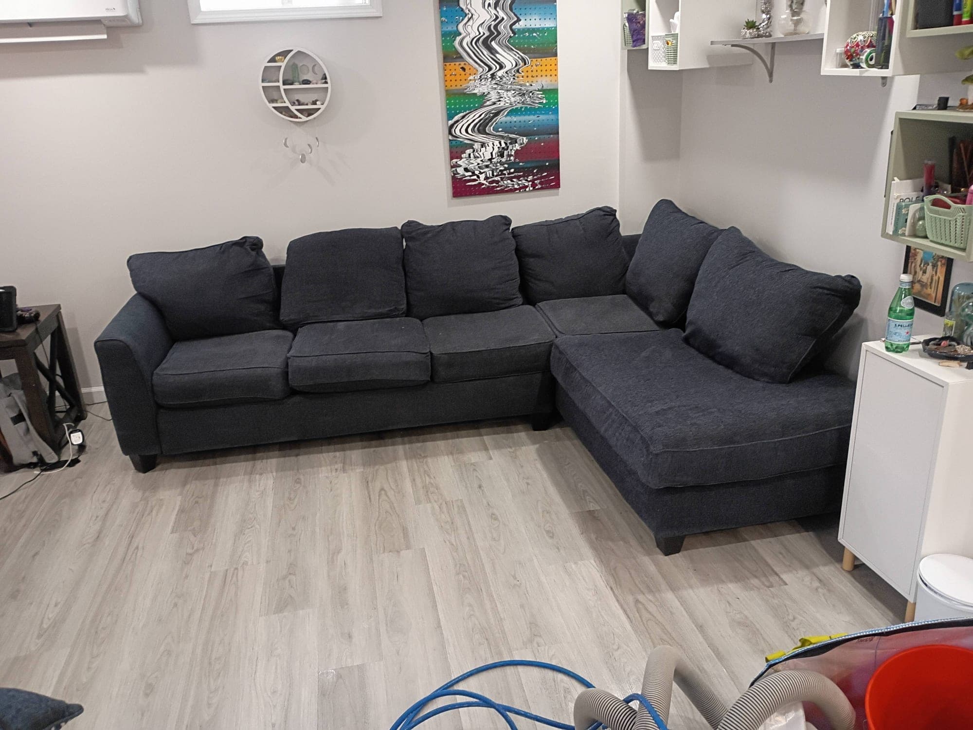 Dark gray sectional sofa in a room with colorful abstract wall art after cleaning