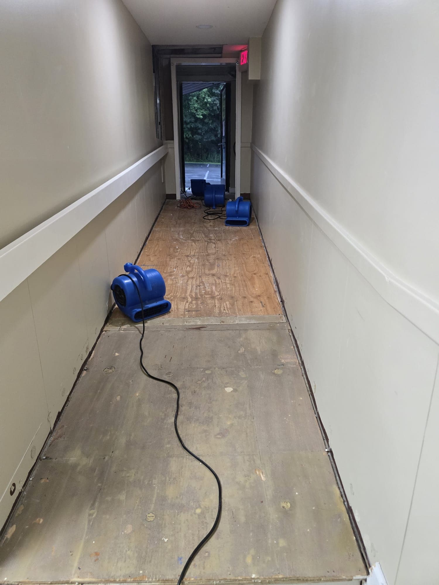 Air mover drying a hallway subfloor after water-damaged flooring was removed