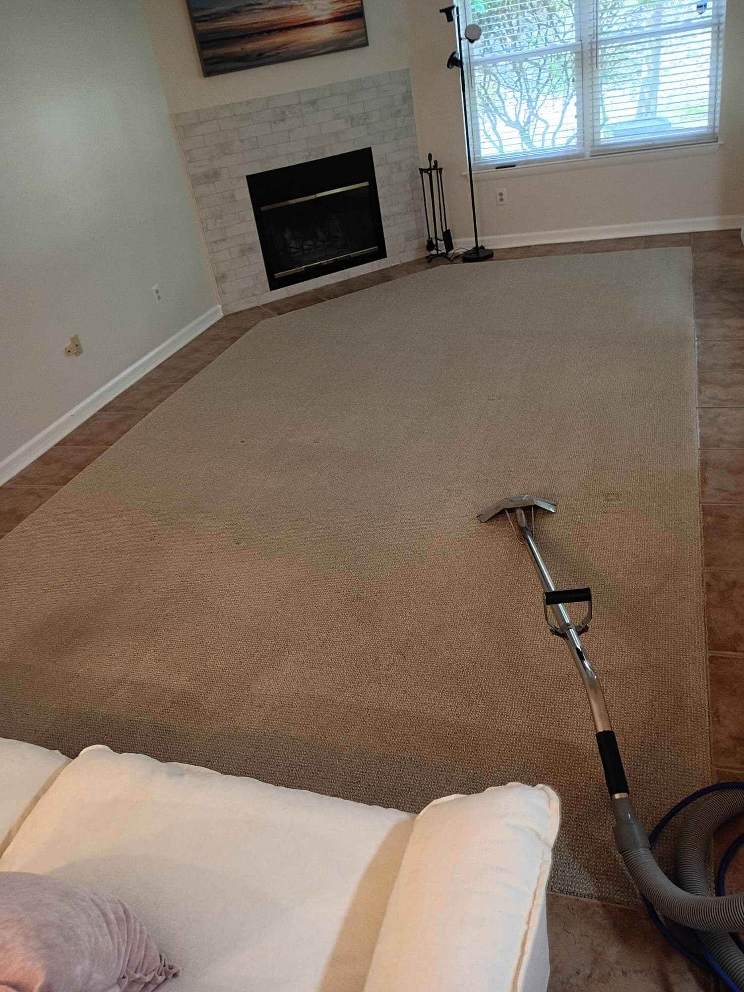 Living room with sectional sofa, fireplace and carpet cleaning wand on the carpet
