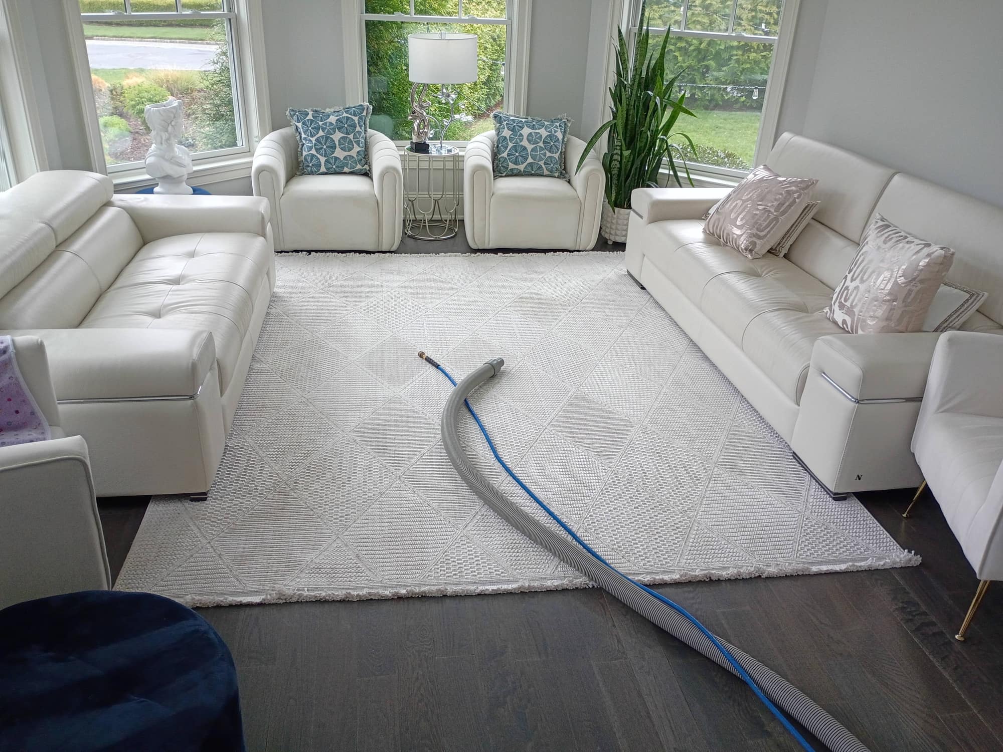 Bright white living room seating set with cleaning hose across the rug