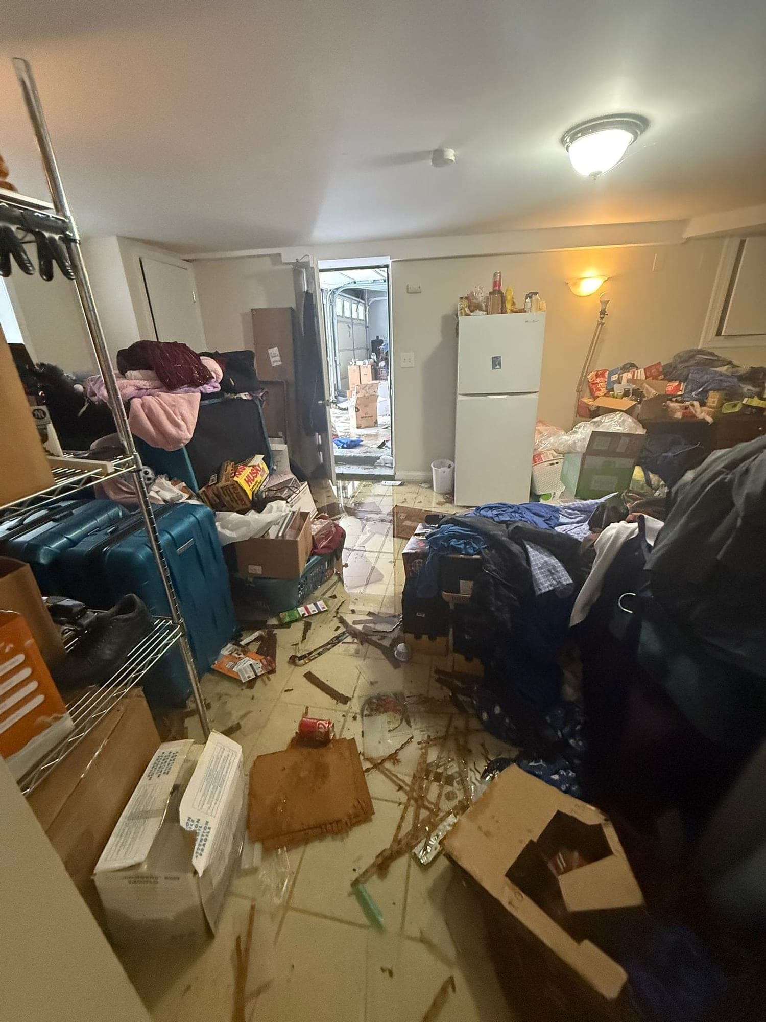 Flooded basement with standing water and soaked belongings near the garage entry
