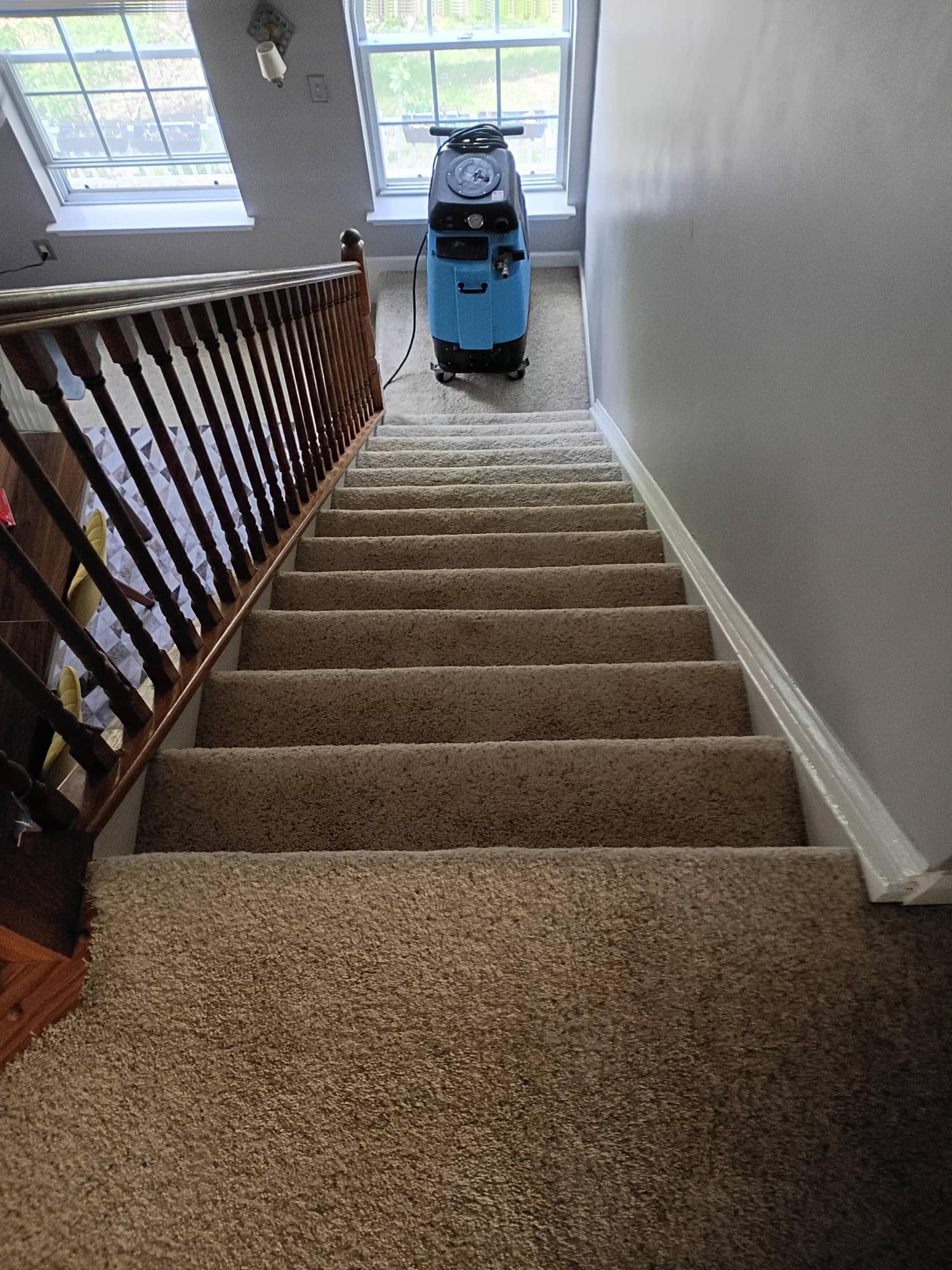 Carpet cleaning machine set up at the top of a staircase in bright natural light