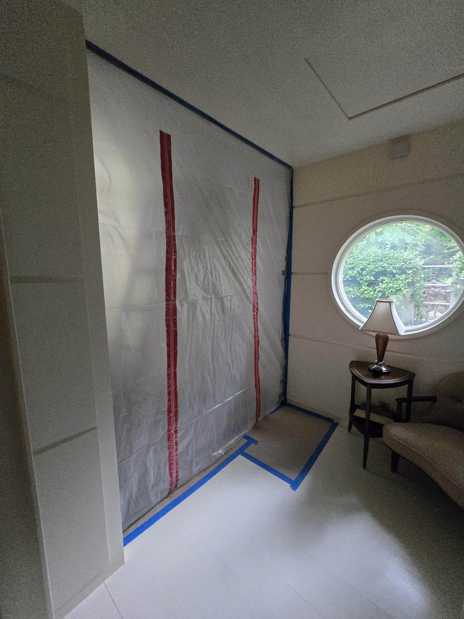 Poly containment wall with red zipper tape sealing off a room beside a round window