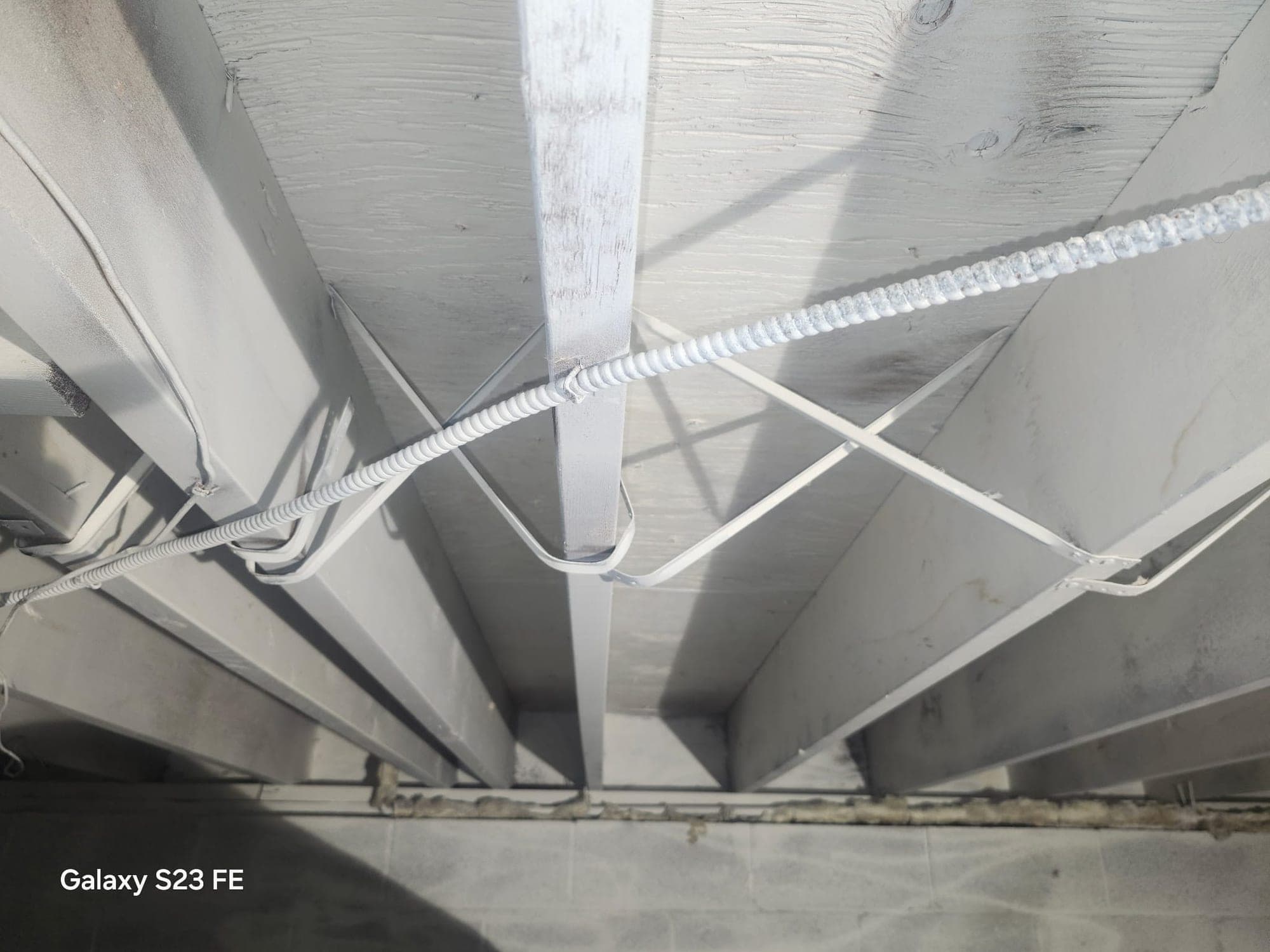 Close-up of crawlspace floor joists fully coated in white mold-resistant encapsulant