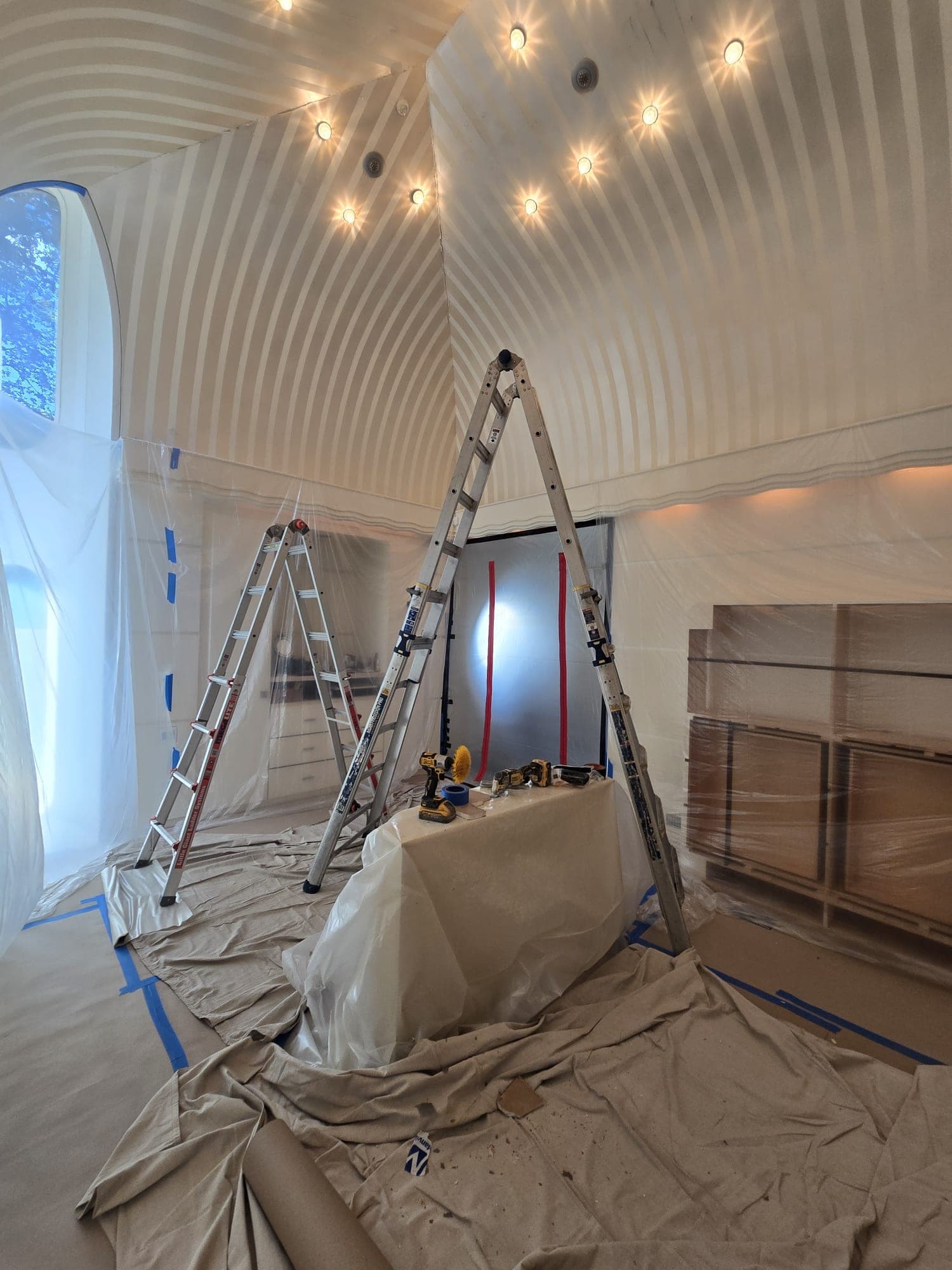 Bedroom fully draped in poly sheeting with ladders set up for ceiling mold work