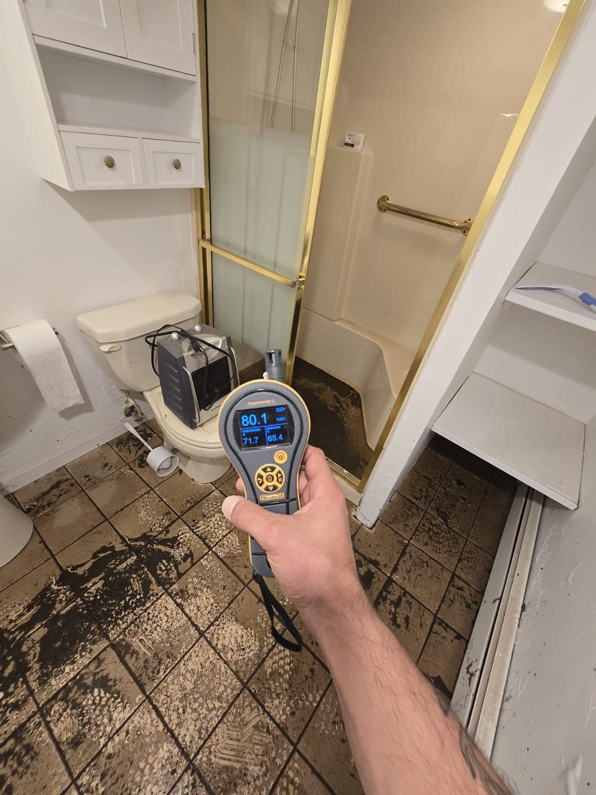 Hygrometer reading 80 percent relative humidity during water damage monitoring in a bathroom
