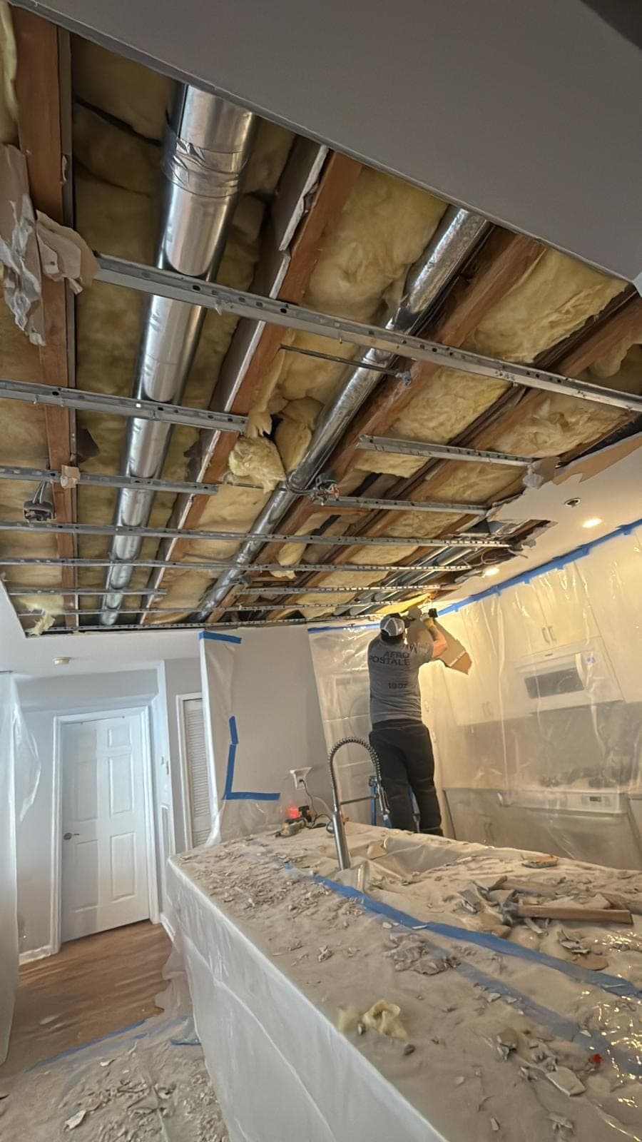 Kitchen ceiling opened after a leak exposing joists, ductwork and saturated insulation