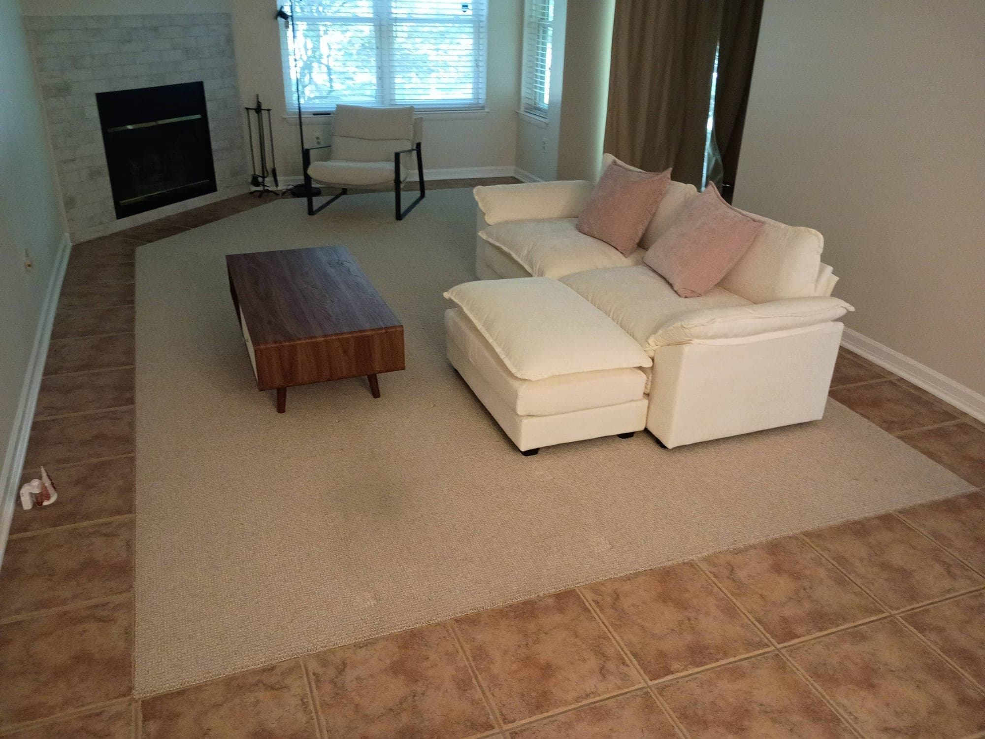 Living room with white sectional sofa and fireplace before carpet cleaning