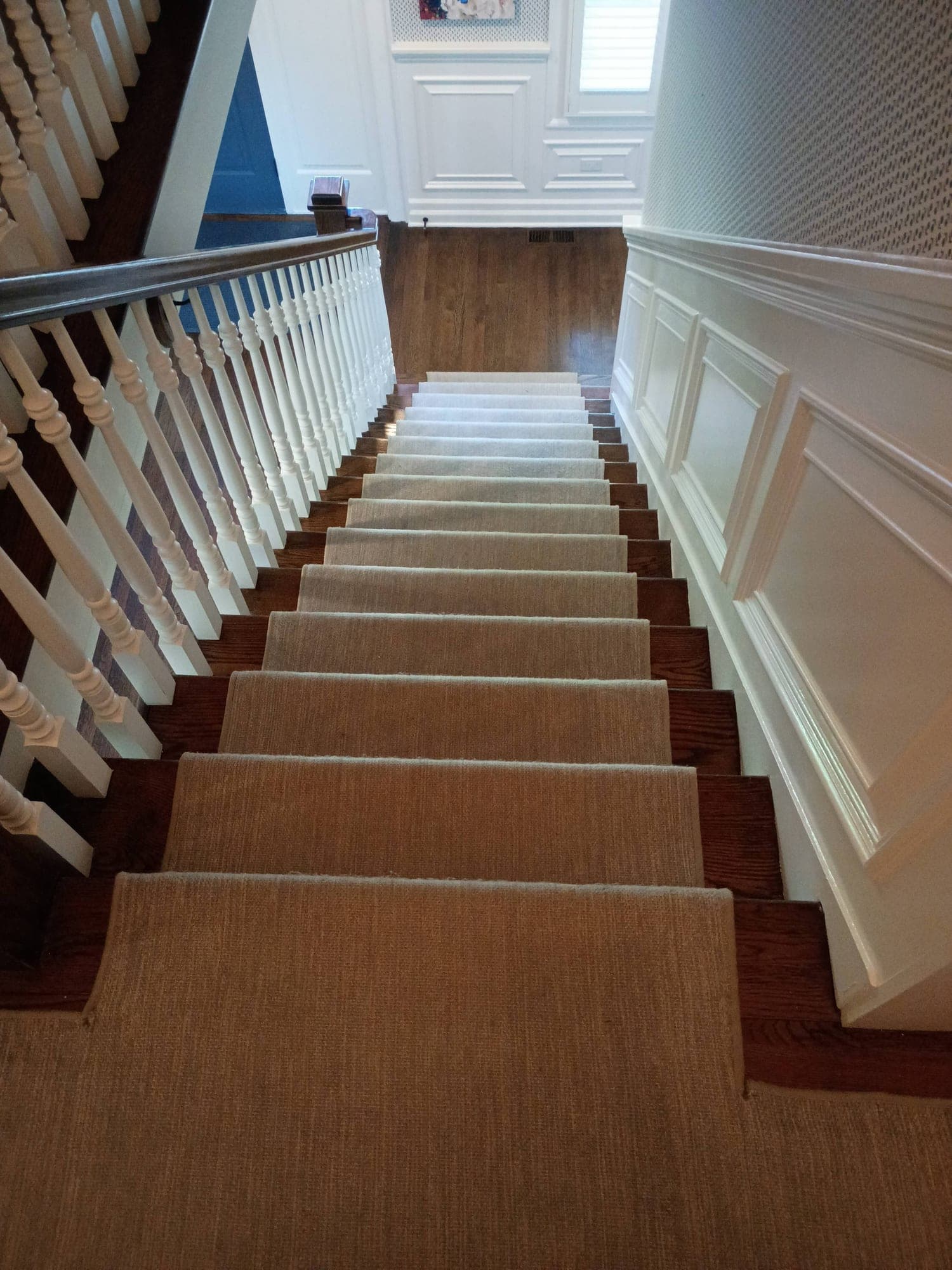 Staircase with natural fiber runner descending two flights in bright light