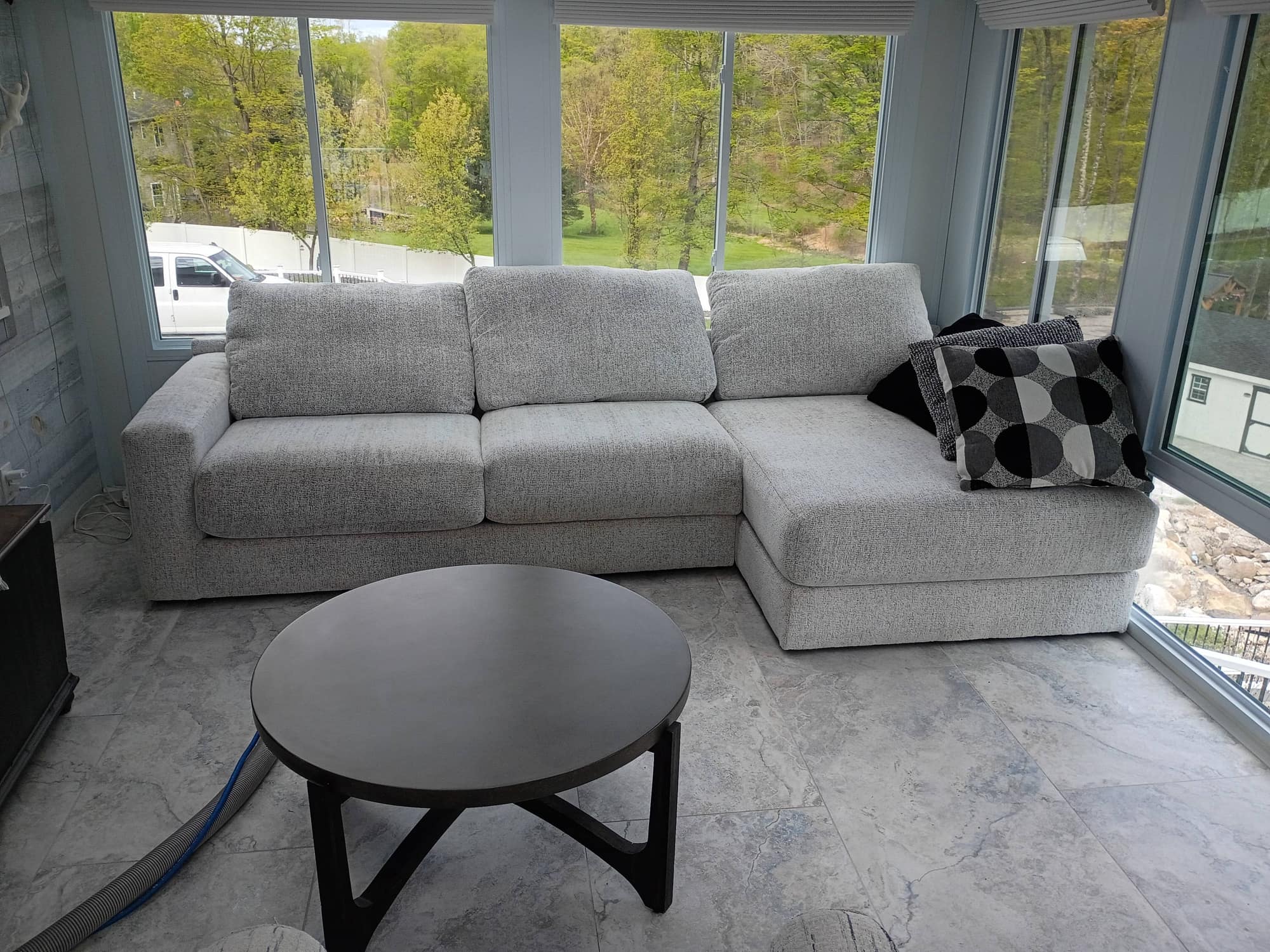 Wide bright sunroom with gray sectional sofa and coffee table after cleaning